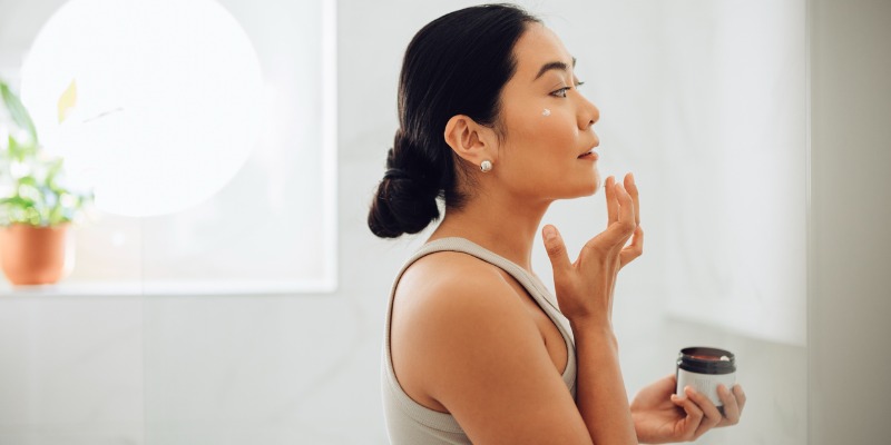 Asian Woman Applying Face Cream In Her Home